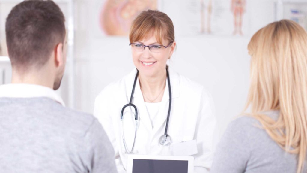 Doctor smiling at man and woman