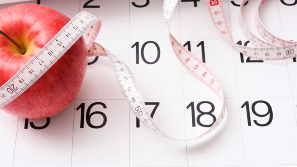 Calendar with apple and measuring tape laying over it