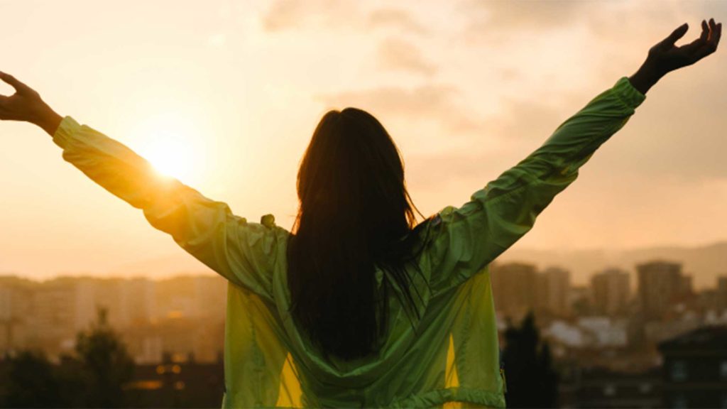 Woman with outstretched arms looking at a city