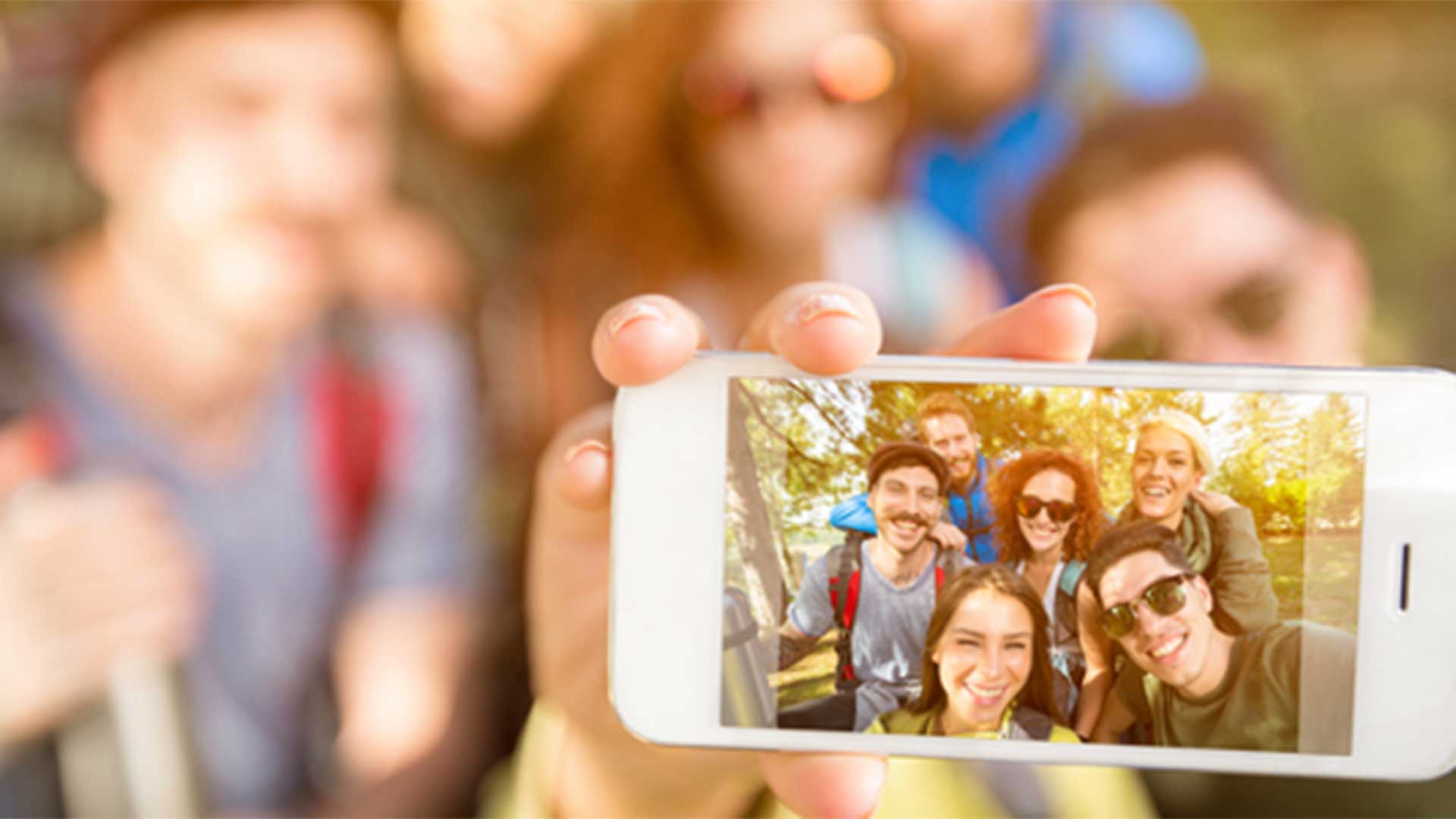 Group of people holding an iPhone and taking a selfie